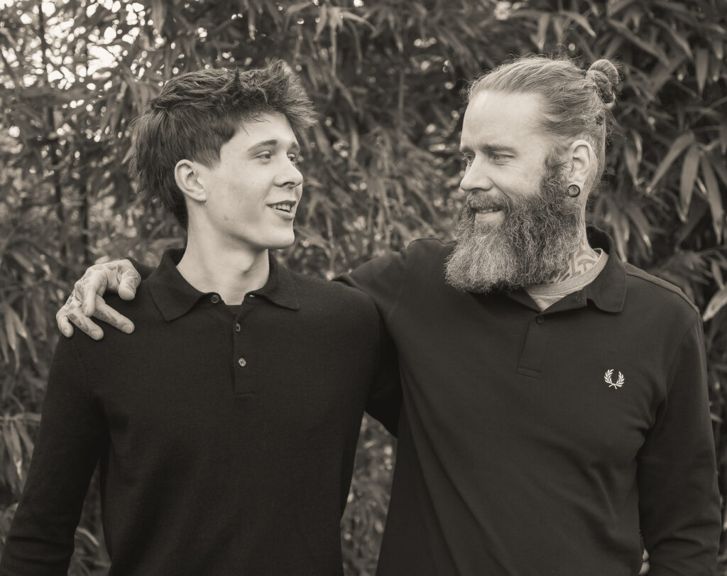 Vater und Sohn stehen nebeneinander und sehen sich an in schwarz weiß fotografiert
