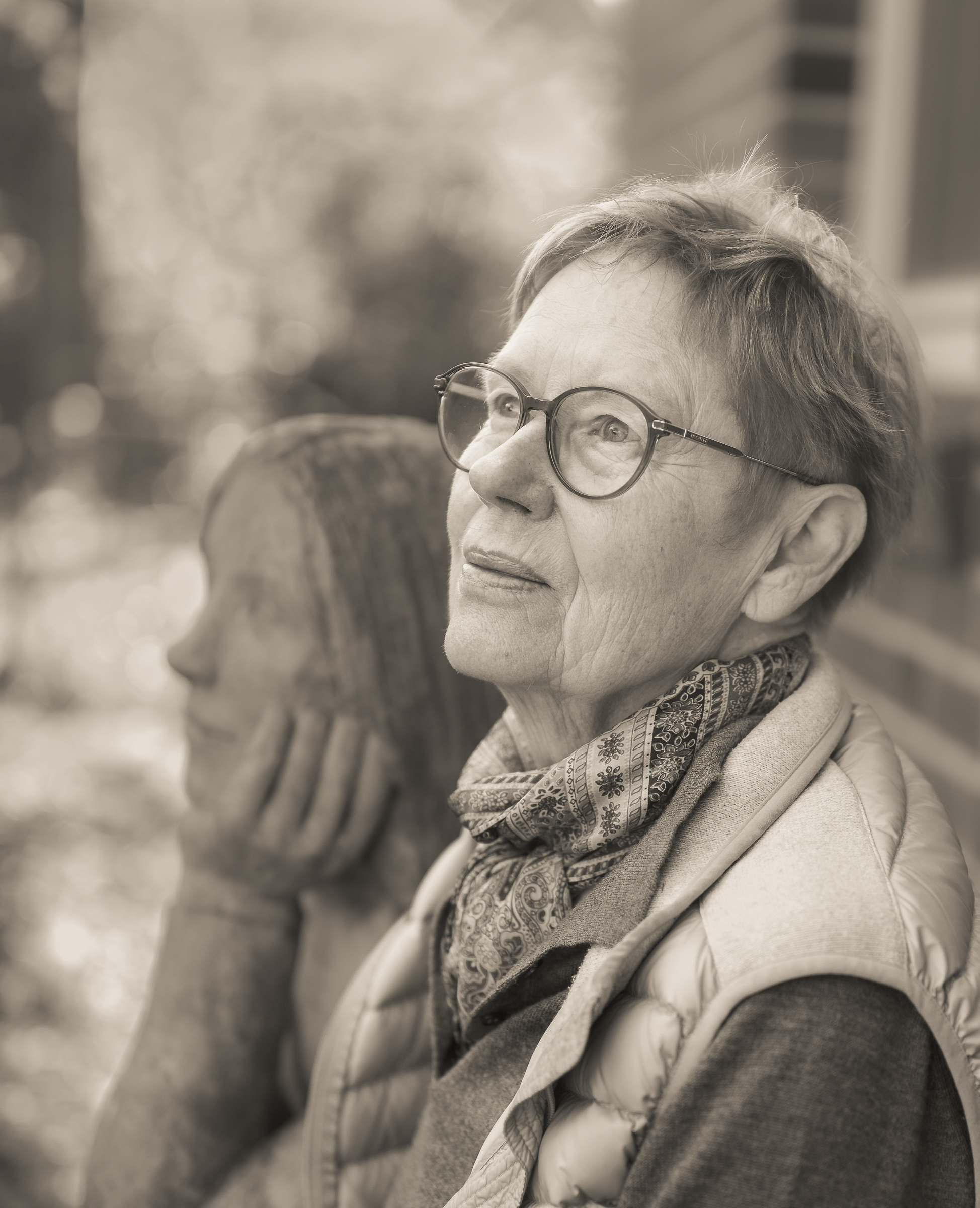 Eine Frau sitzt vor einer Frauenstatur, die sie als Jugendliche darstellt in schwarz weiß fotografiert
