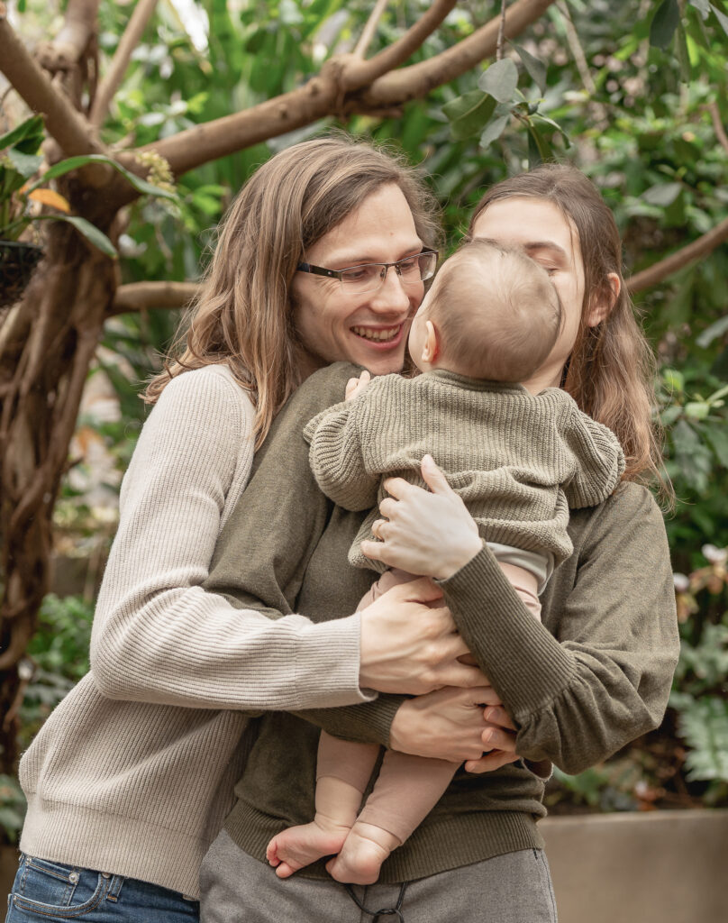 Junges Ehepaar hat das Baby auf dem Arm in einem Tropenhaus
