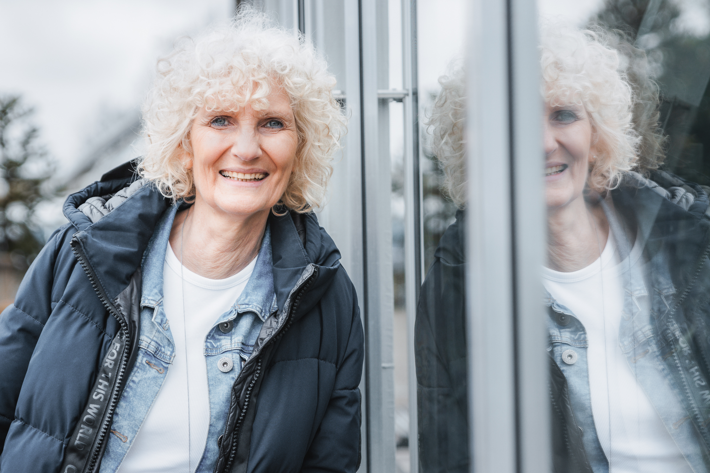 Fotografin lehnt an einer Fensterscheibe und spiegelt sich