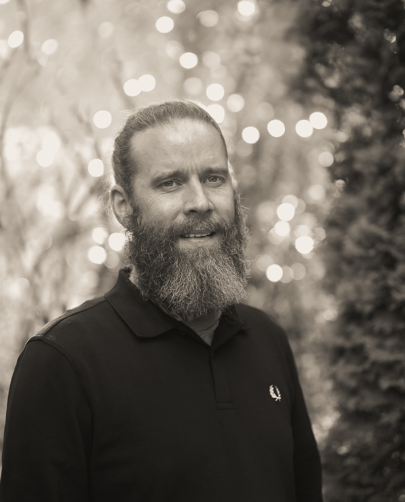 Mann mit Bart schaut freundlich in die Kamera in schwarz weiß fotografiert